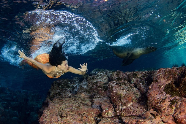 Sirène nageant sous l'eau dans la mer d'un bleu profond avec un phoque