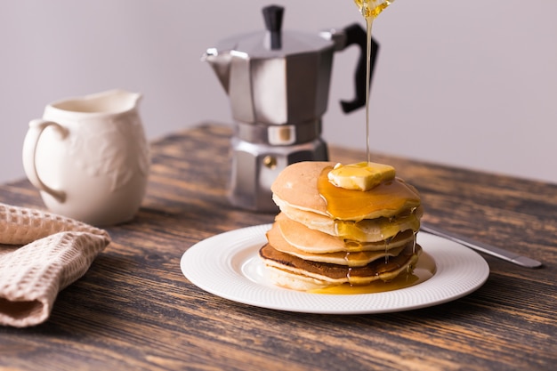 Sirop d'érable versé sur une pile de mini crêpes.