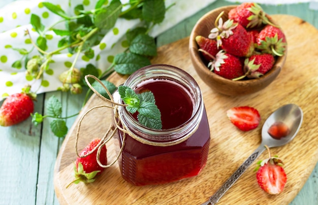 Sirop de fraises et baies de fraises fraîches sur une table en bois