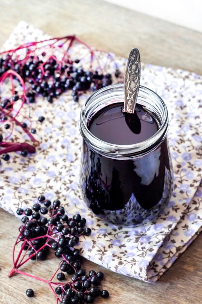 Sirop de sureau noir fait maison dans un bol en verre et un pot