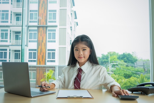 sitplay sourire mignon fille et jouer à l&#39;ordinateur portable dans la bibliothèque