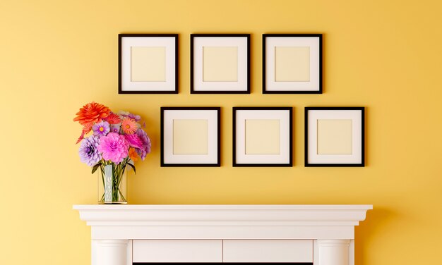 Six cadres photo vierges noirs sur le mur de la pièce jaune ont un vase à fleurs placé sur la cheminée.