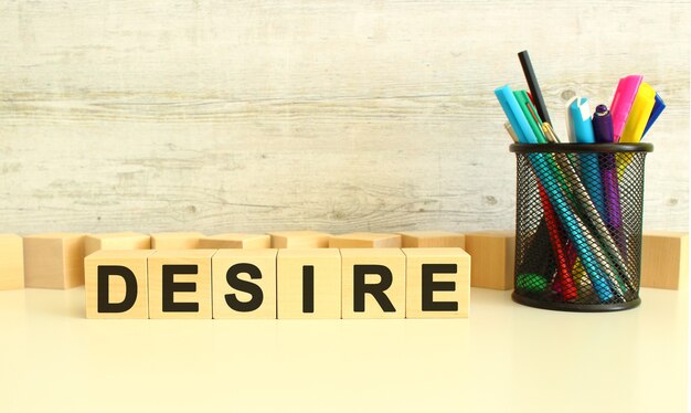 Six cubes en bois empilés avec des lettres DESIRE sur une table de travail blanche sur fond gris