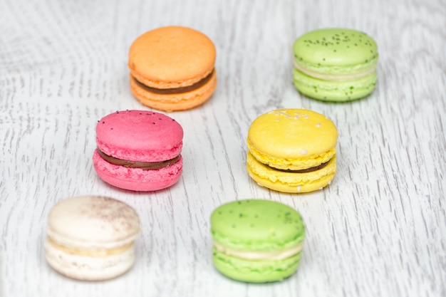 Six macarons multicolores sur une table en bois clair