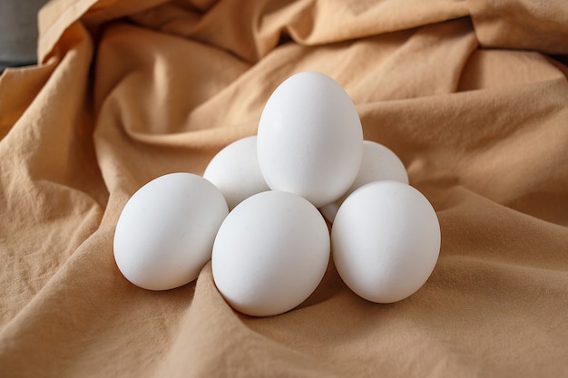 Six oeufs de poule blancs sur fond beige