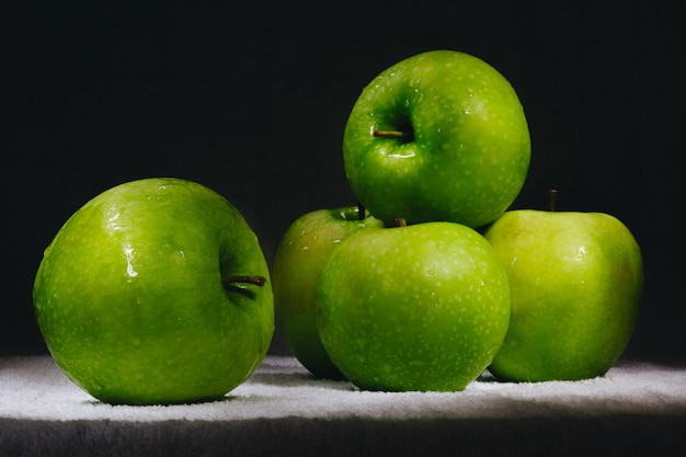 Six pommes vertes fraîches sur un fond sombre