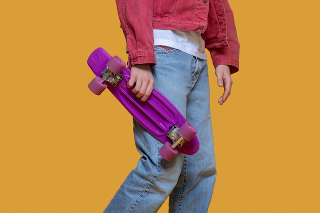 Avec skateboard. Homme en veste rouge tenant une planche à roulettes