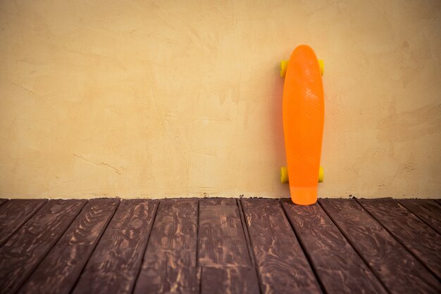 Photo skateboard orange près du mur