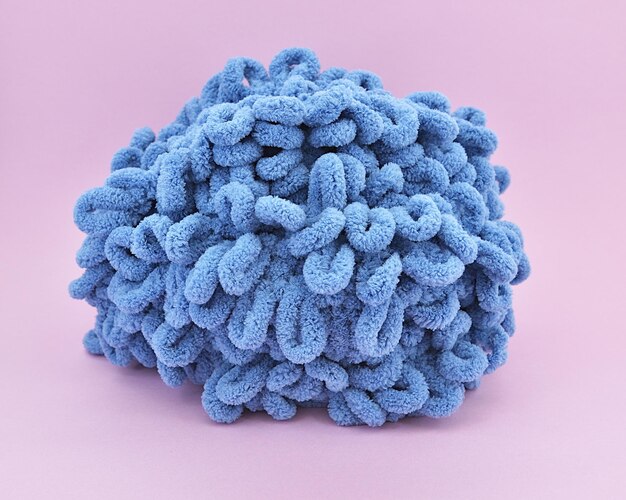 Photo skein de fil gonflé bleu épais à tricoter sur fond rose