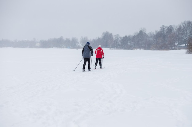 Photo skier en brise-vent et chapeau avec des bâtons de ski dans les mains avec son dos sur le fond d'un