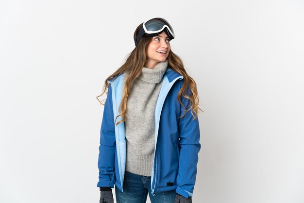 Skieur femme avec des lunettes de snowboard isolé sur blanc pensant une idée tout en levant les yeux