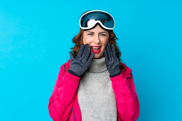 Skieur femme avec des lunettes de snowboard sur mur isolé