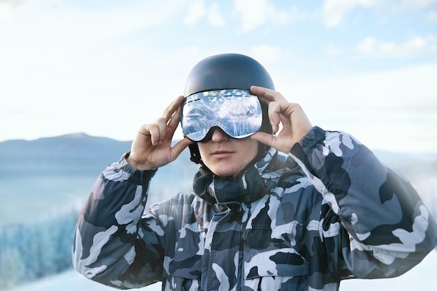 Skieur sur fond de ciel bleu détient des lunettes de ski avec le reflet des montagnes enneigées.. Sports d'hiver.