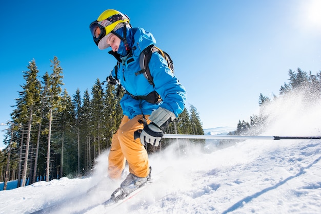 Skieur masculin ski sur la neige fraîche dans les montagnes par une belle journée ensoleillée
