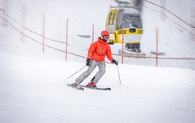 Skieur professionnel en veste rouge descendant la colline rapidement