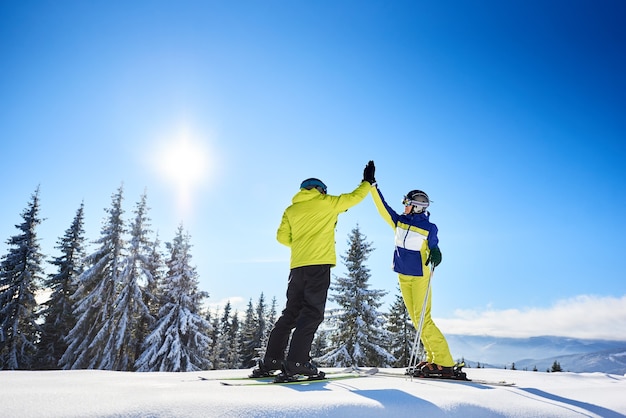 Les skieurs masculins et féminins high cinq à l'autre sous un ciel bleu ensoleillé