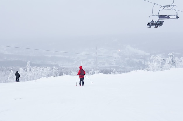 Les skieurs skient en descente et prennent un télésiège dans un paysage hivernal vallonné