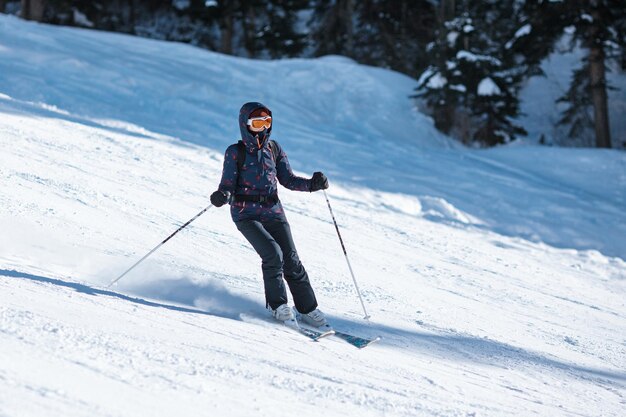 Skieuse amateur glissant sur la pente par une journée ensoleillée dans une station de montagne