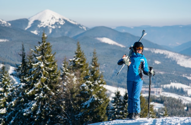 Skieuse debout au sommet d'une montagne avec des skis sur son épaule paysage magnifique