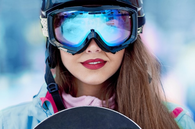 Skieuse souriante et portant des lunettes de ski dans les montagnes