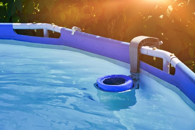 Skimmer sur une piscine à ossature ronde d'une maison de campagne Skimmer bleu pour nettoyer la piscine en eau claire