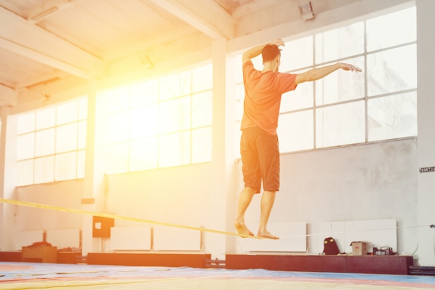 Slackline homme marchant et en équilibre sur une corde, slackline dans une salle de sport