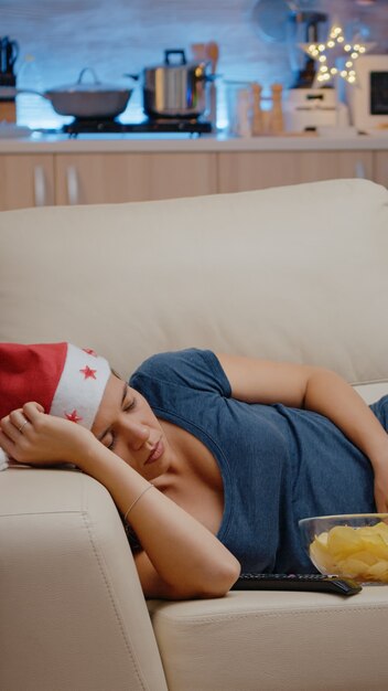 Sleepy woman wearing santa hat et reposant sur un canapé