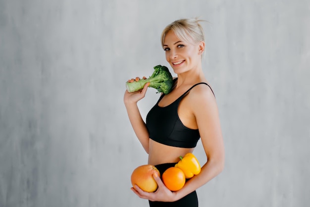 Slim femme heureuse tenant des fruits et légumes frais