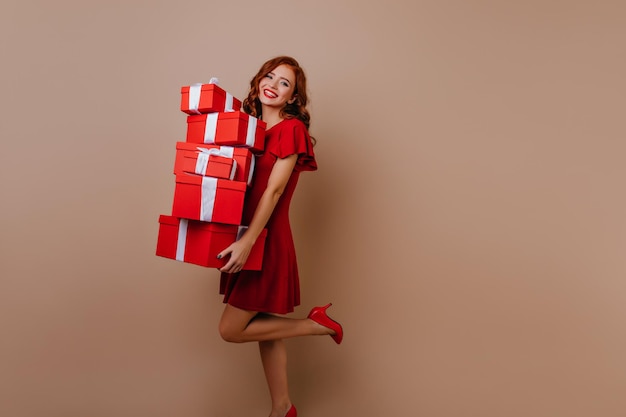 Slim happy woman holding cadeaux d'anniversaire Debonair rire dame posant avec des cadeaux de Noël sur fond beige