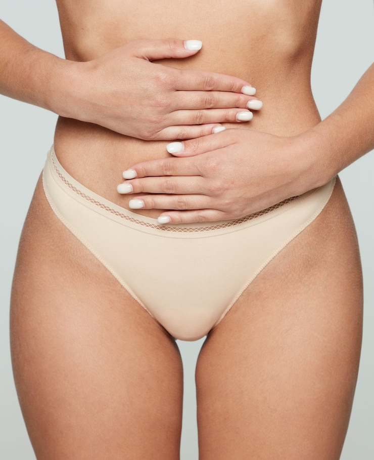 Photo slim taille féminine sur fond blanc avec ses mains sur son ventre