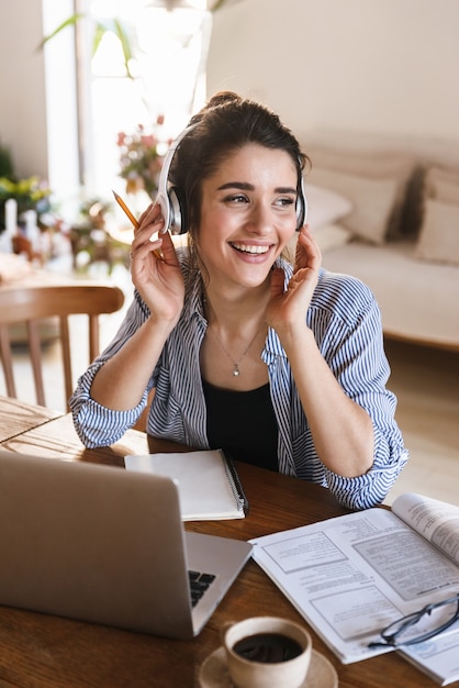 Smart Jolie Femme Dans Les écouteurs écouter De La Musique Tout En Travaillant Ou En étudiant Sur Un Ordinateur Portable à La Maison