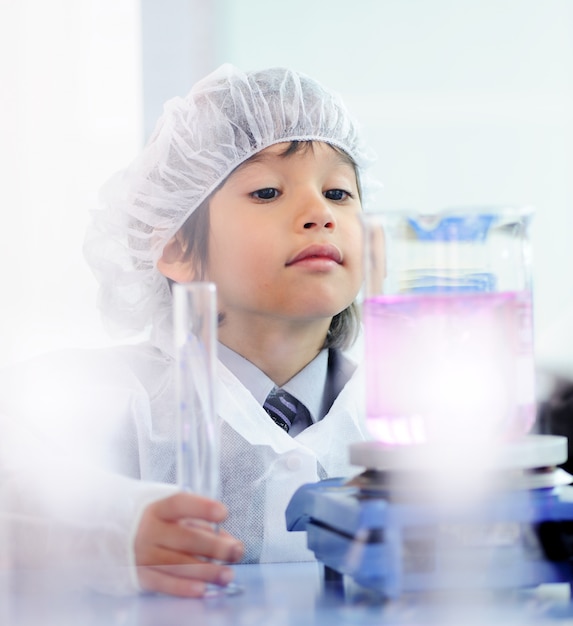 Smart mignon petit enfant mâle expérimenter avec des tubes à essai dans le vrai laboratoire de l&#39;hôpital moderne