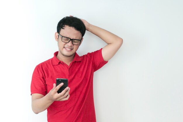 Smart Young Asian man est confus et insiste sur le fait qu'il regarde son smartphone en arrière-plan studio