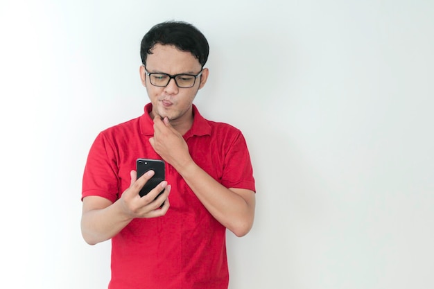 Smart Young Asian man est confus et insiste sur le fait qu'il regarde son smartphone en arrière-plan studio