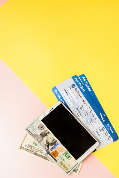 Smartphone, billet d'avion et dollars