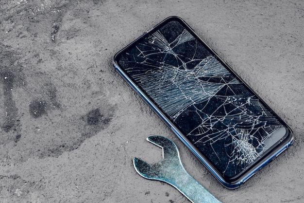 Smartphone crashé avec des outils de réparation sur gris