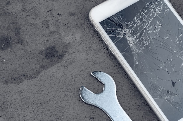 Smartphone crashé avec la réparation d'outils sur fond gris