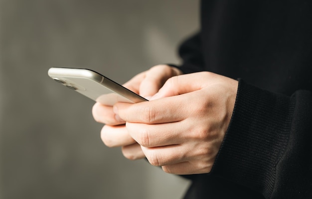 Smartphone dans les mains d'un homme gros plan sur un arrière-plan flou le concept d'utilisation de la technologie shopping en ligne communiquant à distance