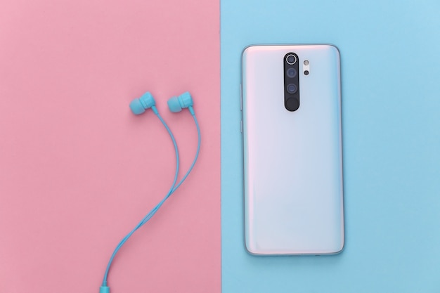 Smartphone et écouteurs sur pastel bleu-rose