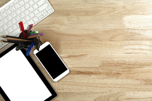 Smartphone écran blanc et tablette PC sur le bureau en bois et clavier blanc