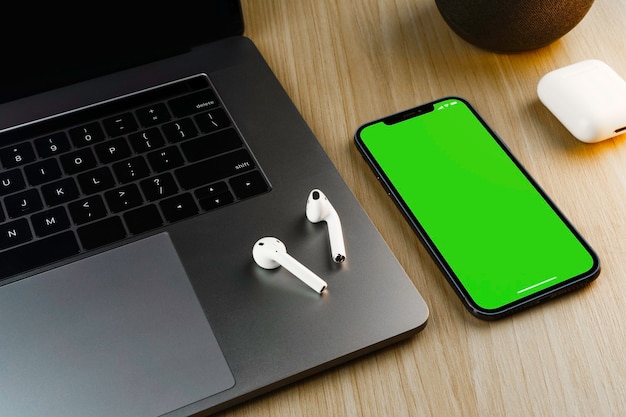 Smartphone avec un écran vert sur fond en bois avec un ordinateur. Vue de dessus. Clé chroma.