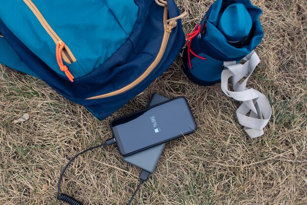 Le smartphone est chargé à l'aide d'un chargeur portable. Power Bank charge le téléphone à l'extérieur avec un sac à dos pour le tourisme dans la nature.