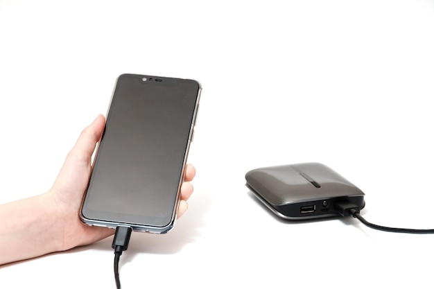 Le smartphone est un enfant dans la main des enfants à partir d'un câble Powerbank de batterie externe et d'un téléphone sur fond blanc