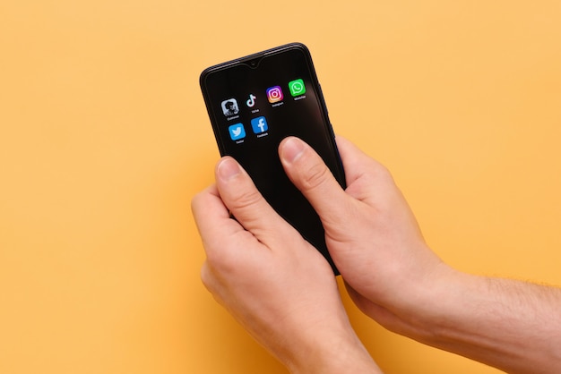 smartphone avec des icônes des applications de médias sociaux tendance dans la main d'un homme