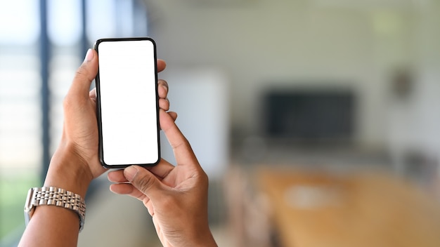 Smartphone sur les mains avec écran vide et salle de réunion