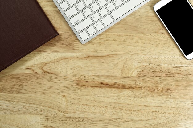 Smartphone moderne avec écran blanc et un clavier sur la table en bois