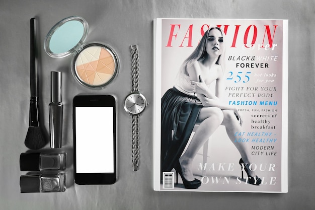 Photo smartphone de montre-bracelet de cosmétiques et magazine sur la vue de dessus de fond gris