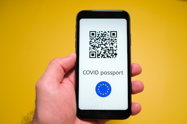 Un smartphone avec passeport de santé numérique immunitaire électronique covid pass avec code qr dans la main de l'homme