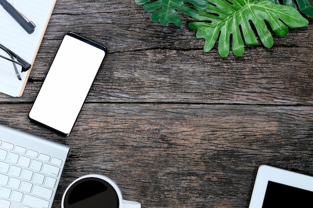 Smartphone sur table en bois et fournitures avec clavier et café