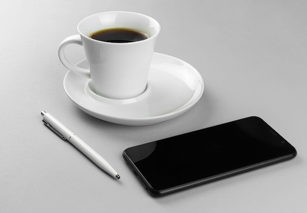 Smartphone tasse de café et stylo blanc sur fond gris